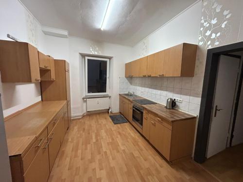 an empty kitchen with wooden cabinets and a window at Ferienwohnung Kinheim an der Mosel in Kinheim