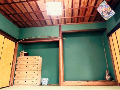 a room with a green wall and a wooden ceiling at ポートサイドSasebo藤原町 in Sasebo