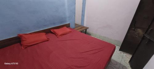 a red bed with two red pillows on it at Annu Bhai Sewa Sadan in Mathura