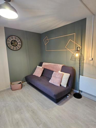 a couch in a room with a clock on the wall at Appartement 1-4 personnes, Résidence "Le Belouga" in Le Mont-Dore