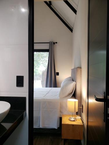 a bedroom with a bed and a sink and a mirror at Tiny House na Pousada Hortelã-Pimenta in Itirapina