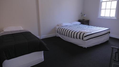 a bedroom with a white bed and a white bedspread at National Hotel Toowoomba in Toowoomba