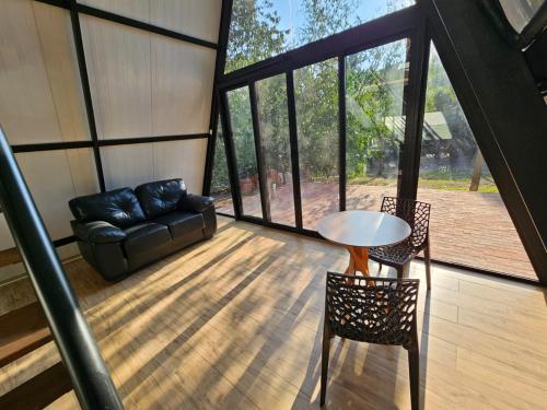 a living room with a couch and a table and chairs at Chalé na Pousada Hortelã-Pimenta in Itirapina