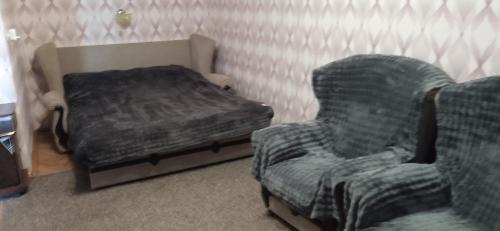 a bedroom with a bed and a chair next to a couch at Квартира 2х-комнатная посуточно in Kryvyi Rih