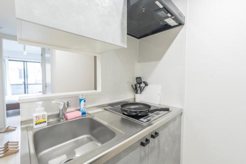 Una cocina con un fregadero y una sartén sobre una encimera. en 三ノ輪駅徒歩圏 交通便利 浅草観光 ショッピング グルメを満喫する日本堤ステイ DsL, en Tokio