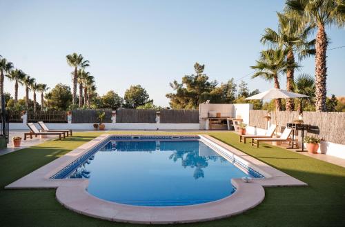 a swimming pool with chairs and palm trees in a yard at La casa Zamora in Totana