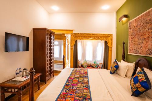 a bedroom with a large bed and a television at Tripli Hotels Surya Villas in Jaisalmer