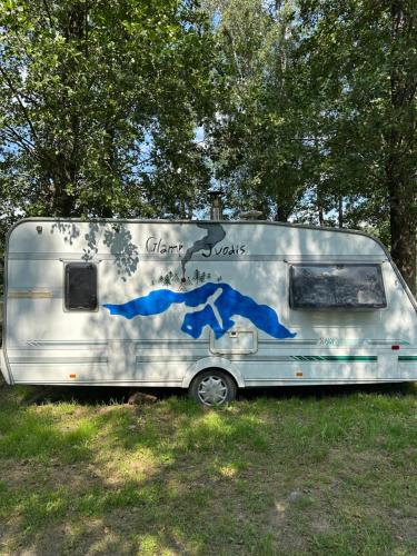 a silver caravan parked in a field with trees at Glamp Juodis in Ubiškės