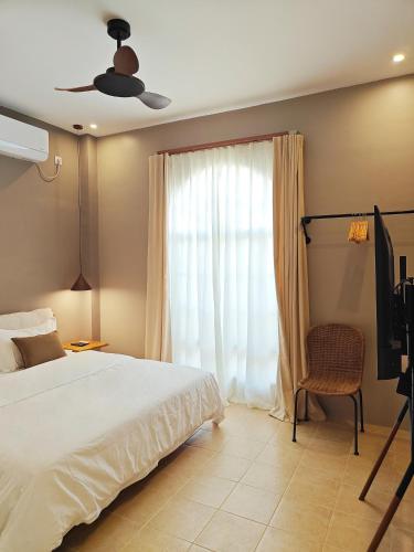 a bedroom with a bed and a tv and a window at The Palm House in Dauis