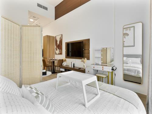 a white bedroom with a white bed and a table at Savis Homes - Luxury Brand New Studio in Elysee III in JVC in Dubai