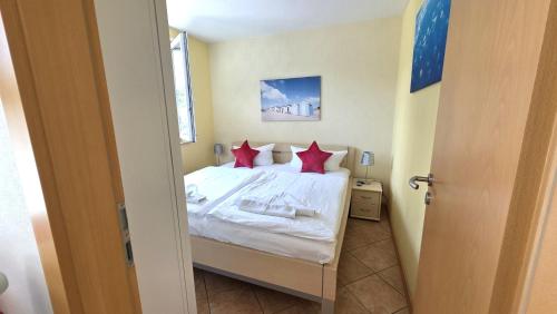 a bedroom with a white bed with red pillows at Strandburg, das smarte Penthouse in ÜckeRitz mit PKW Stellplatz! in Ueckeritz