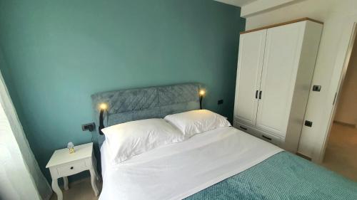 a bedroom with a white bed and a blue wall at Apartman Fortis in Knin