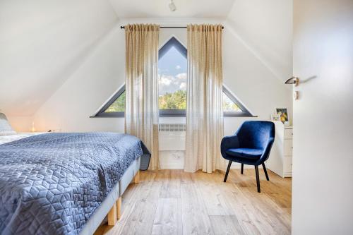 a bedroom with a large window and a blue chair at Bory Za Oknem in Tleń