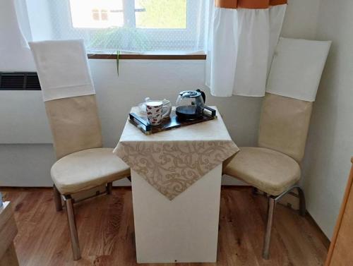 a small table with two chairs and a table with a tea kettle on it at Apartmán Pod Hvězdami in Štítary