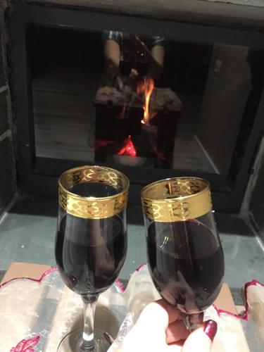 two glasses of red wine in front of a fireplace at Vila Culli in Përmet