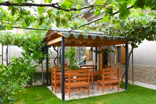 a wooden gazebo with chairs and tables in a garden at Vila Culli in Përmet