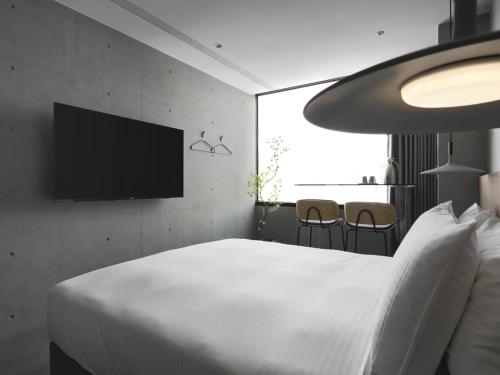 een slaapkamer met een wit bed en een flatscreen-tv bij Miu Hostel in Tainan