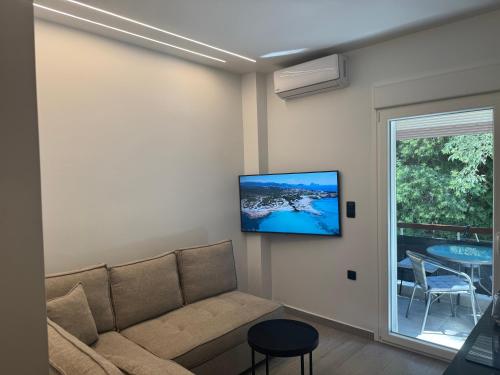 a living room with a couch and a tv on the wall at Luxury Apartment Bedro in Nea Kalikratia