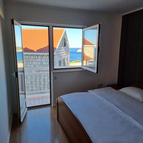 a bedroom with a bed and a large window at Apartments Kutlic in Cavtat