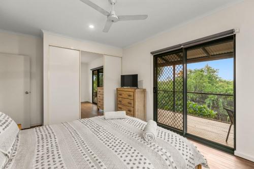 a white bedroom with a bed and a large window at Beach Retreat on Demco in Broome