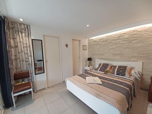 a bedroom with a large bed and a chair at T1 Cosy "Clairefont" Terrasse privée vue Loire dans Maison in Aurec-sur-Loire