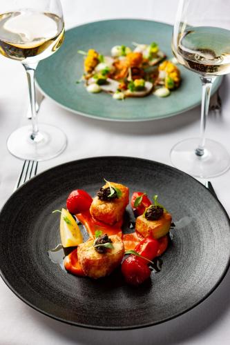 a black plate with food on a table with glasses of wine at Morley Hayes Hotel in Derby