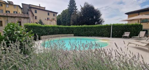 a swimming pool in a yard with chairs and a building at Casa Brown - con piscina privata - in Barga