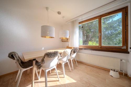 a dining room with white chairs and a wooden table at Marlenca 2 by Arosa Vacations, Familienwohnung mit Bergblick in der Nähe des Skilift-Kulm in Arosa