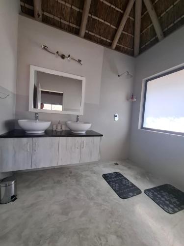 a bathroom with two sinks and a mirror at Amukela Kaya in Hoedspruit
