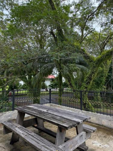 a wooden picnic table in front of a fence at Clover Studiostay in Labuan