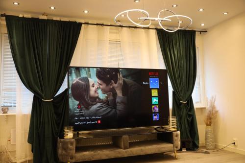 a flat screen tv in a living room with green curtains at Between the Trees in Gothenburg
