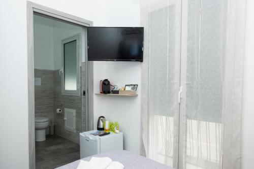 a bathroom with a toilet and a television on a wall at Punta mare in Marsala