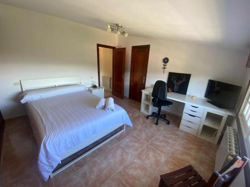 ビーゴにあるÁtico con vistas y aparcamiento gratuitoのベッドと机とテレビのある寝室