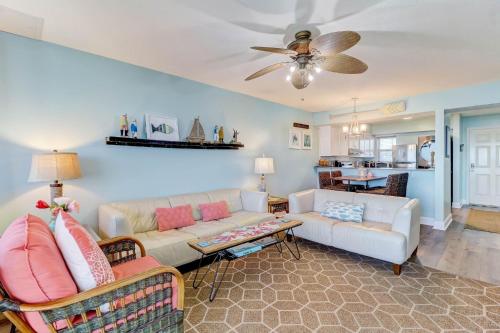 a living room with two couches and a ceiling fan at Condo w Google Mini Home in Fernandina Beach