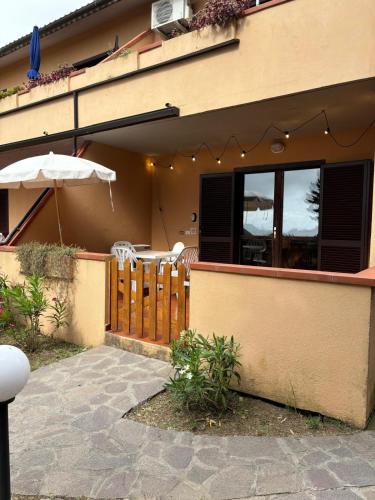 a house with a fence and an umbrella and a patio at Casa dell'Acqua - Isola d'Elba in Rio nellʼElba
