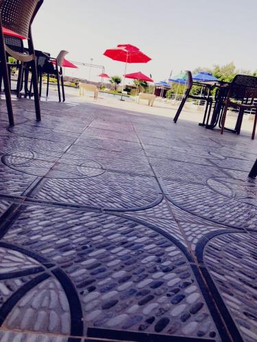 a patio with tables and chairs and an umbrella at Hotel Family Park in Marrakech