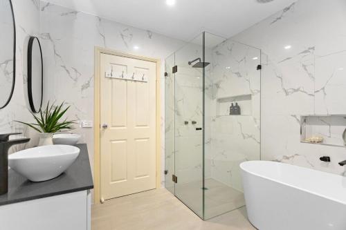 a bathroom with a shower and a tub and a sink at Villa beach Austinmer in Austinmer