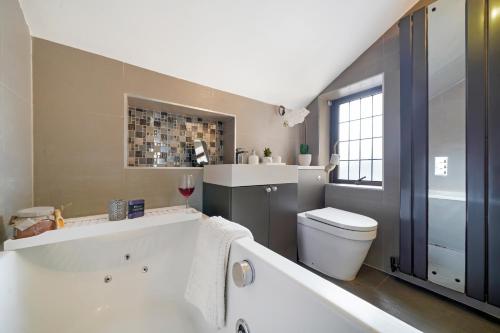a bathroom with a white tub and a toilet at 2 King 4 Singles 2 Sofa Beds Driveway Parking x 3 Private Garden Decking in Hillingdon