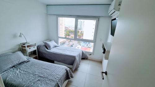 a small room with two beds and a window at LUX TOWER Punta del Este Port in Punta del Este