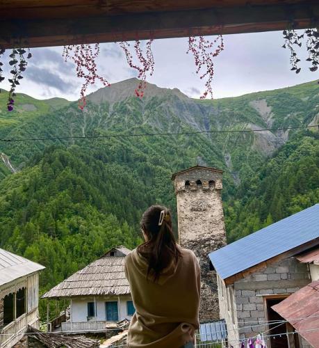 a woman standing on a balcony looking out at a mountain at Bata GuesThouse in Adishi