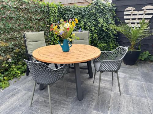 a wooden table with chairs and a vase of flowers at Balsemientexel in De Koog