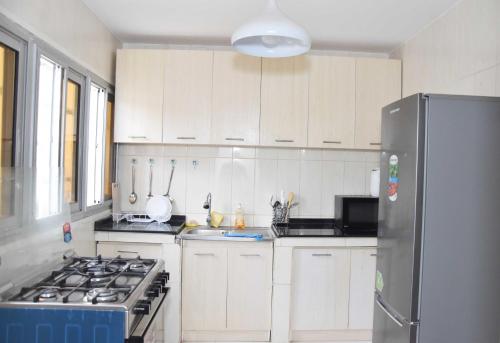 a kitchen with white cabinets and a stainless steel refrigerator at Cosy by dalyda in Yaoundé