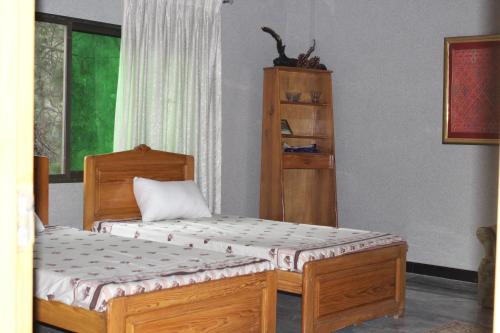 a bedroom with two beds and a book shelf at Dera Qazi Family Studio Apartment in Abbottabad
