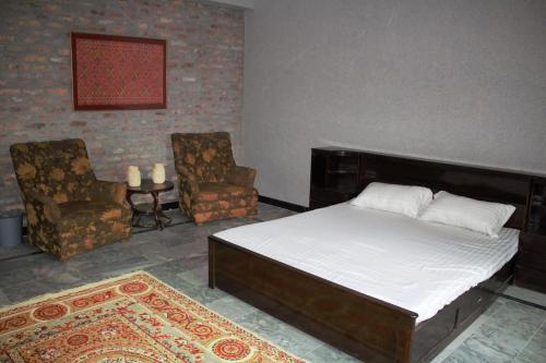 a bedroom with a bed and two chairs and a rug at Dera Qazi Family Studio Apartment in Abbottabad