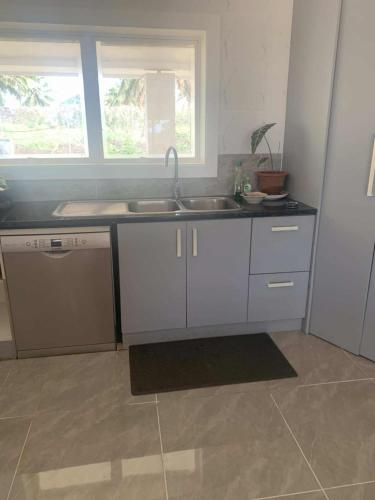 a kitchen with white cabinets and a sink and a window at Toafa Elidad Airport Lodge 