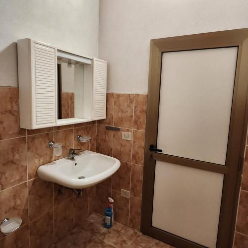 a bathroom with a sink and a mirror and a door at REZIDENCA ARBNORE - Tre Horizonte in Koplik