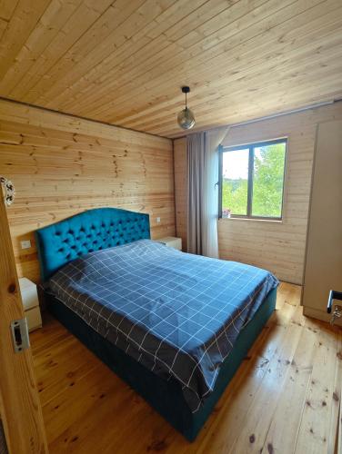 a bedroom with a blue bed in a wooden room at Qusarion - ქუსარიონი in Agara