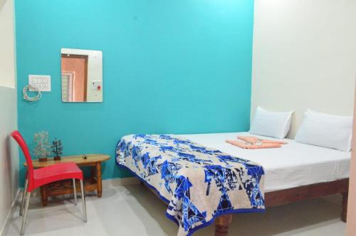 a blue room with a bed and a red chair at Hamsa Home Stay in Hampi