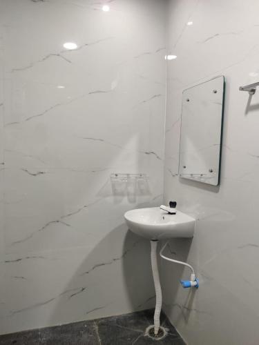 a white bathroom with a sink and a mirror at Hamsa Home Stay in Hampi