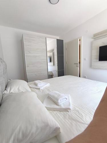 a white bedroom with two beds and a mirror at Apartman Vujanac in Vrnjačka Banja